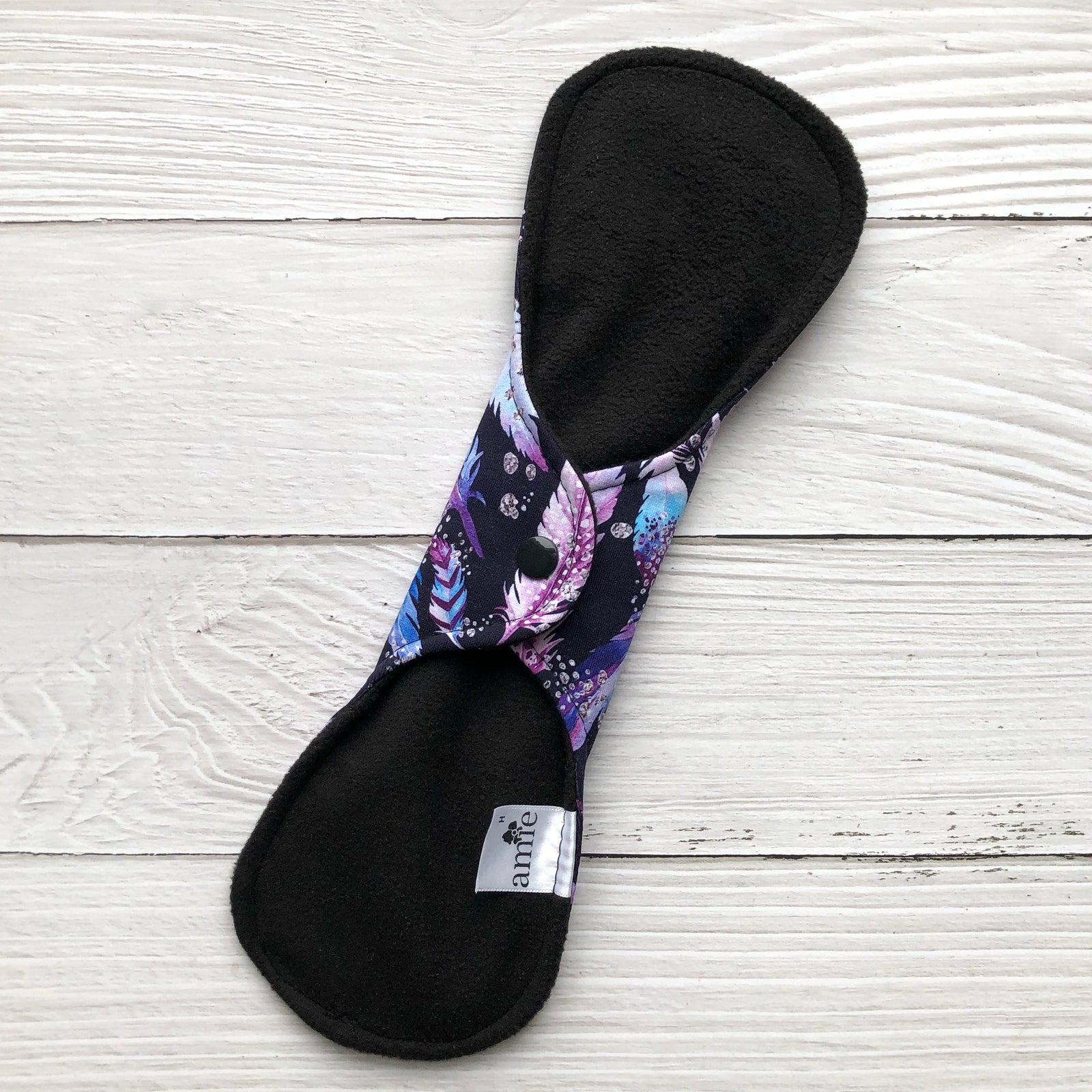 back of snapped reusable pad on white wooden backdrop