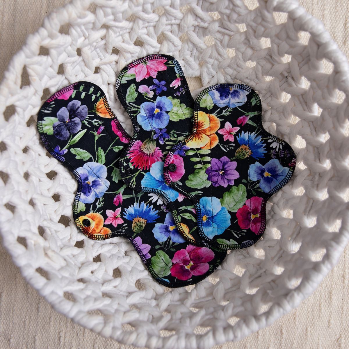 set of three pretty floral print reusable pads in a round white wicker basket