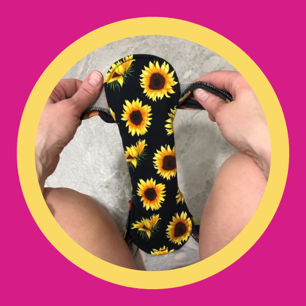 cute black reusable pad with sunflower print being put on