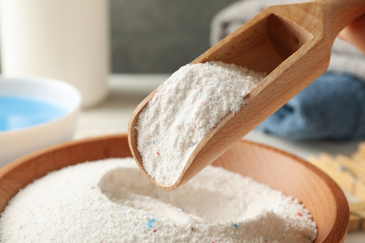 powdered laundry detergent being scooped with a wooden scoop