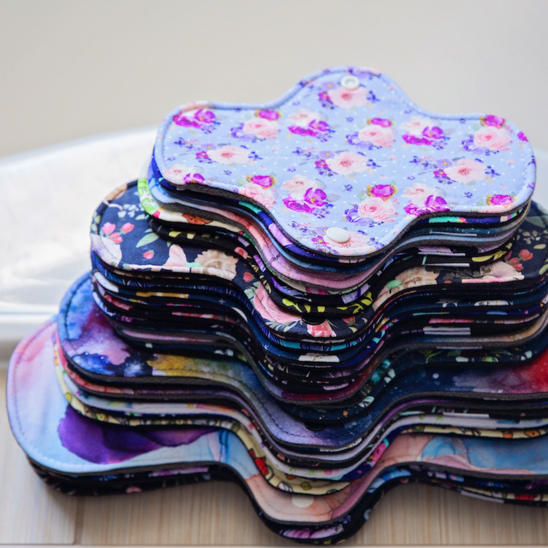 stack of beautiful print reusable pads in various sizes on a bathtub ledge