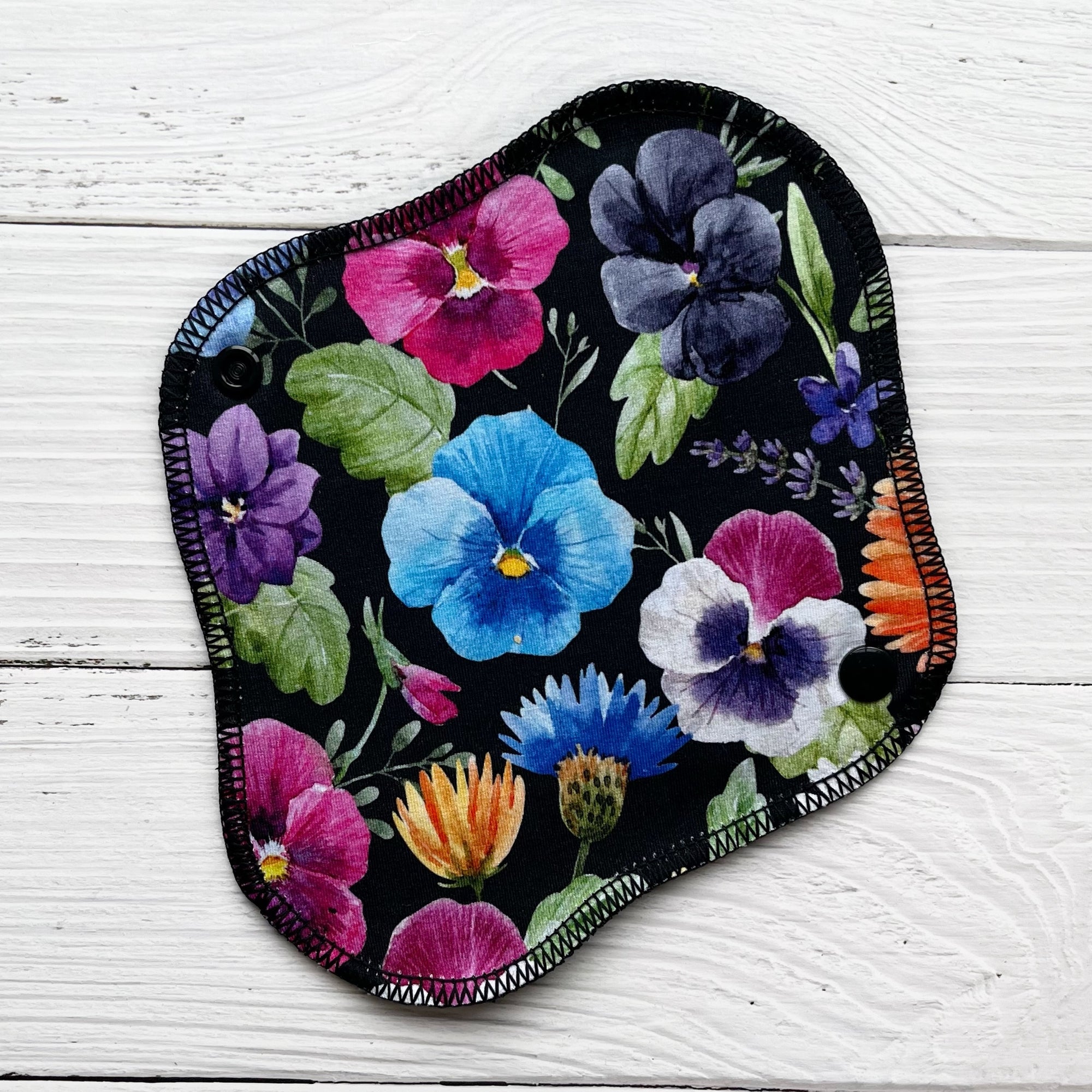 reusable pantyliner in bold pansy print with a black background