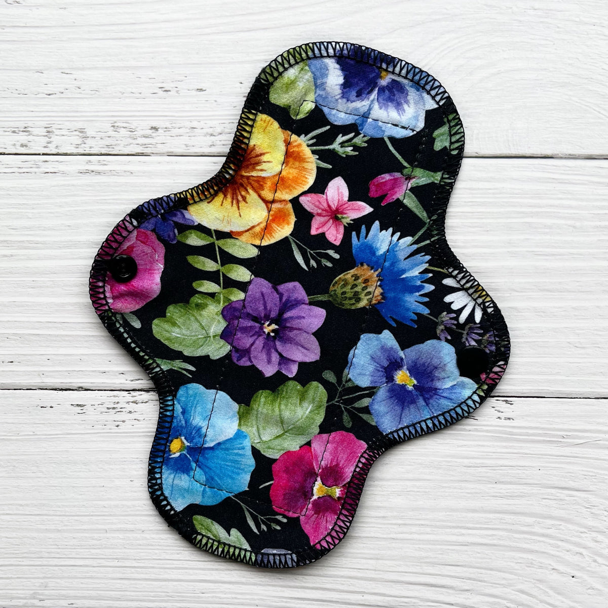 reusable pad with a bold pansy print on a black background