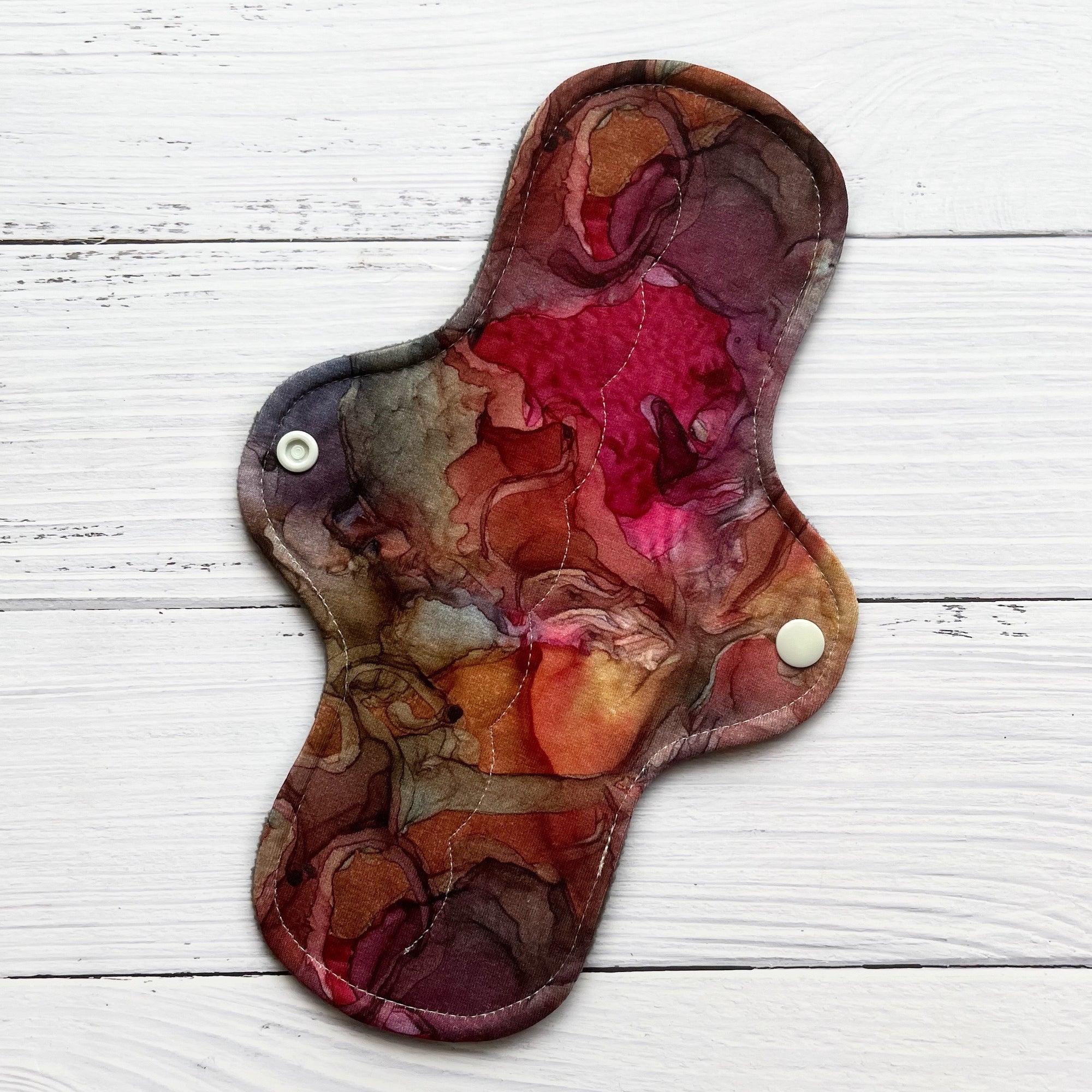 reusable pad in an earthy and jewel toned alcohol ink print