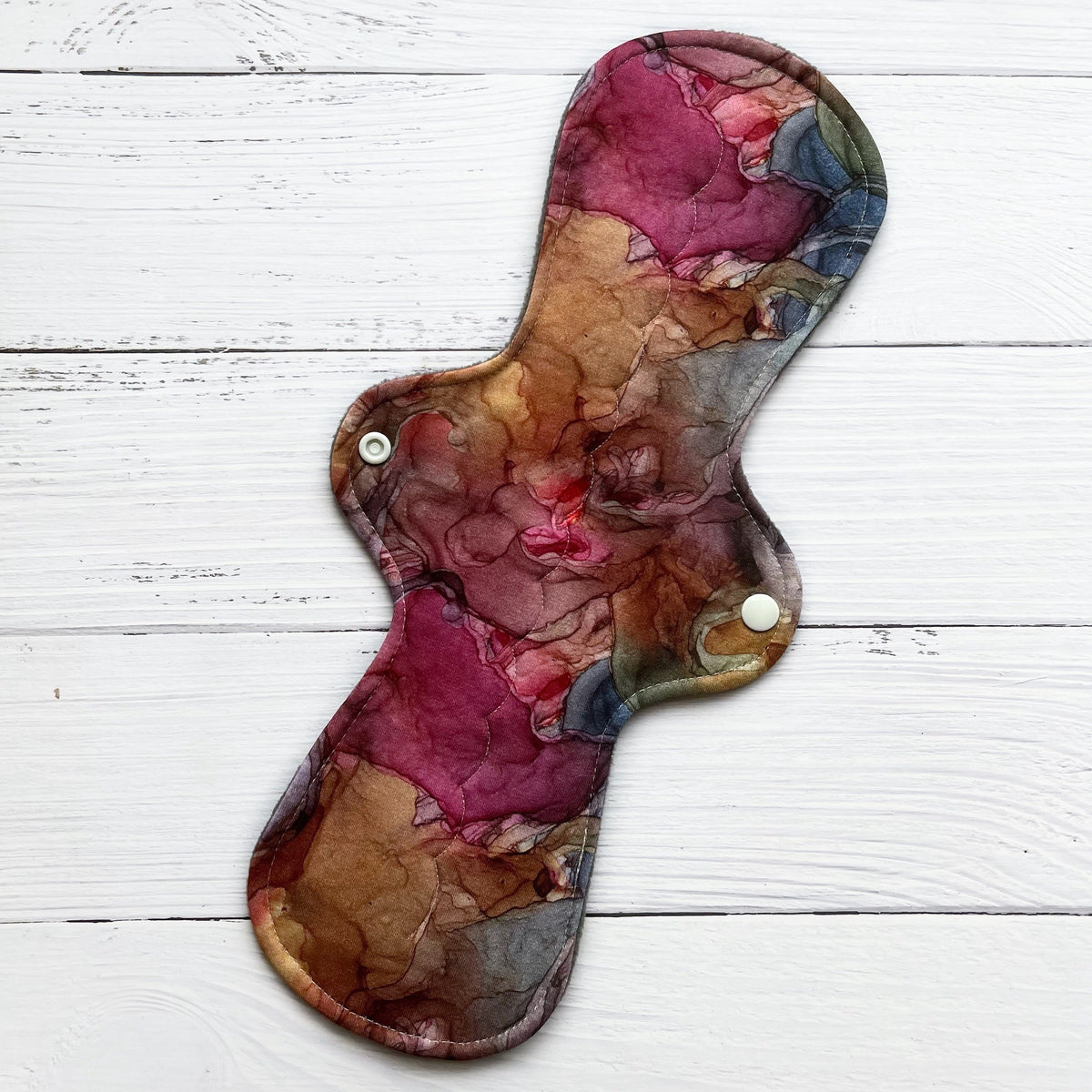 reusable pad in an earthy and jewel toned alcohol ink print