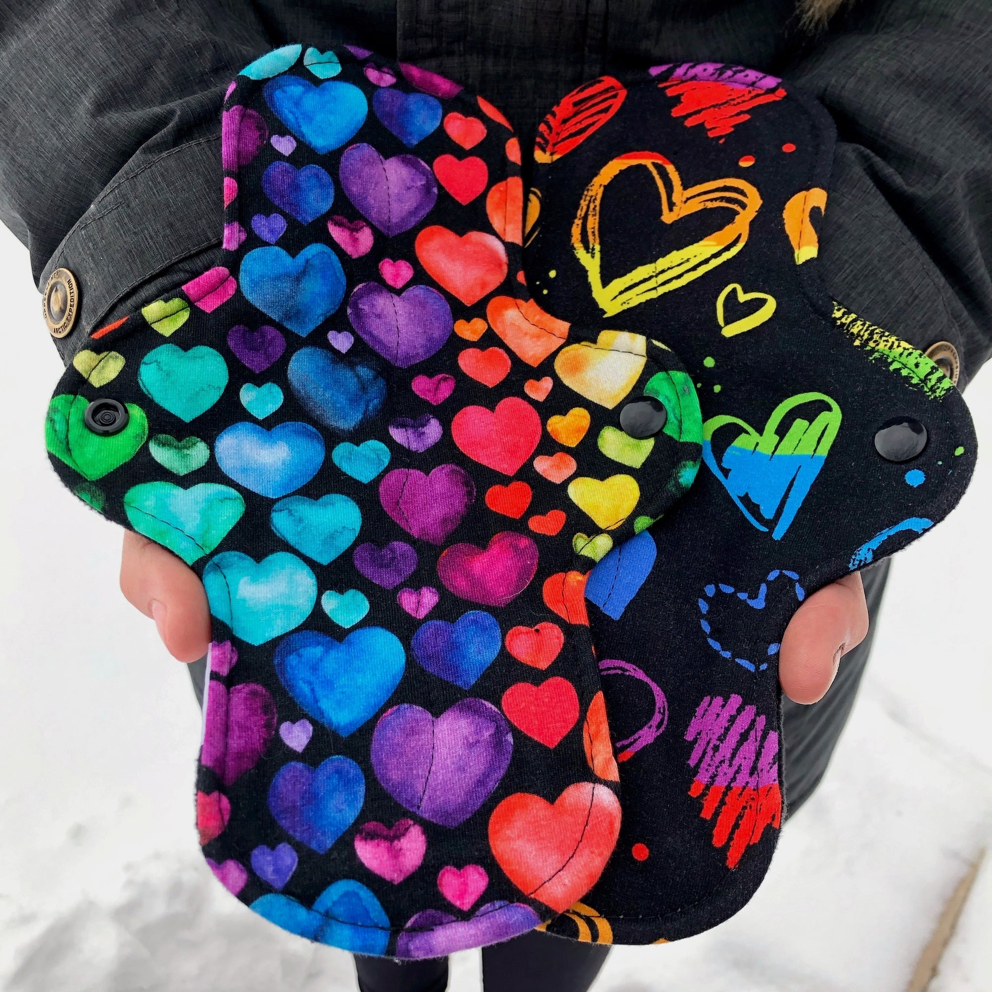 two brightly coloured reusable pads held in outstretched hands