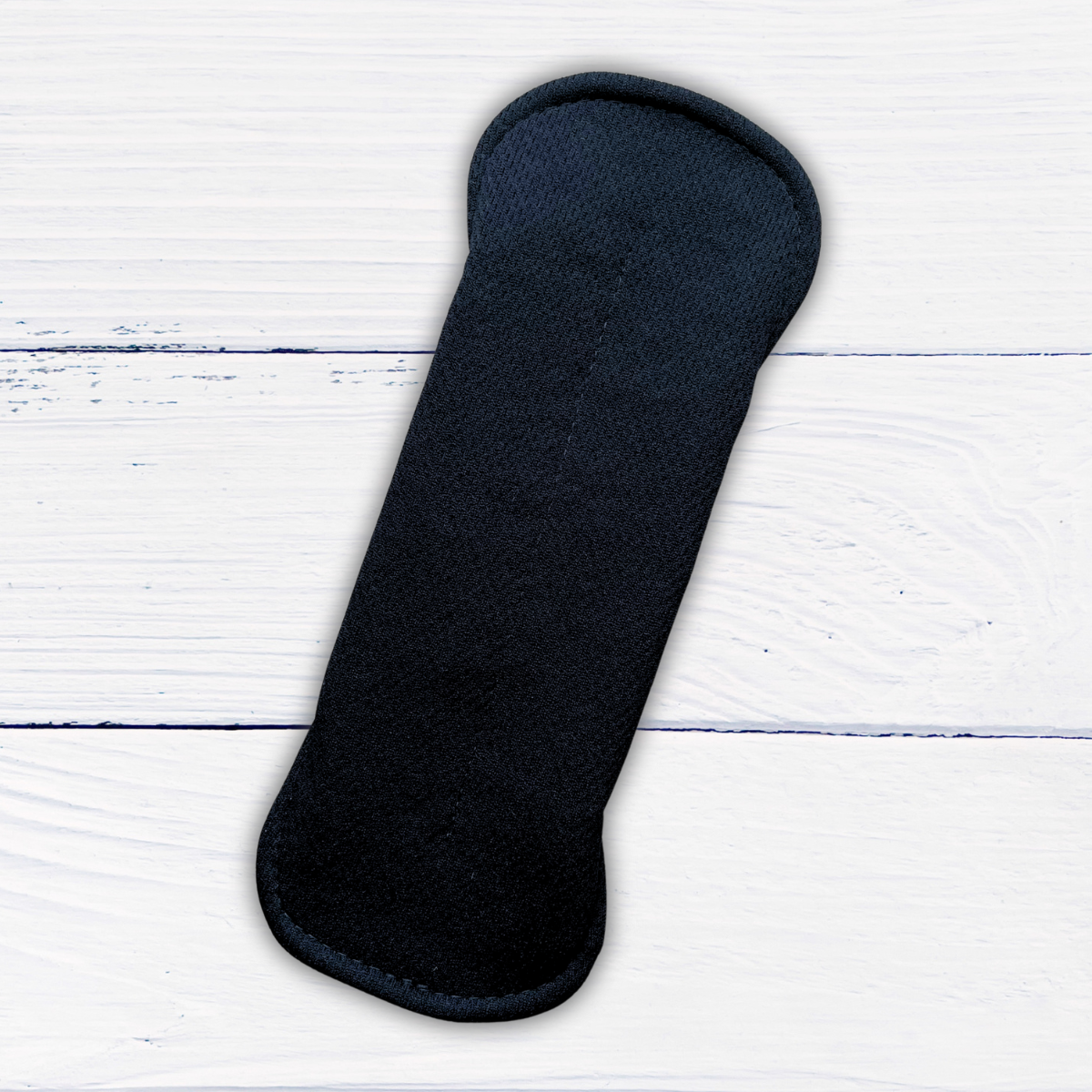 amie active light absorbency Black reusable pad on a rustic white wooden surface