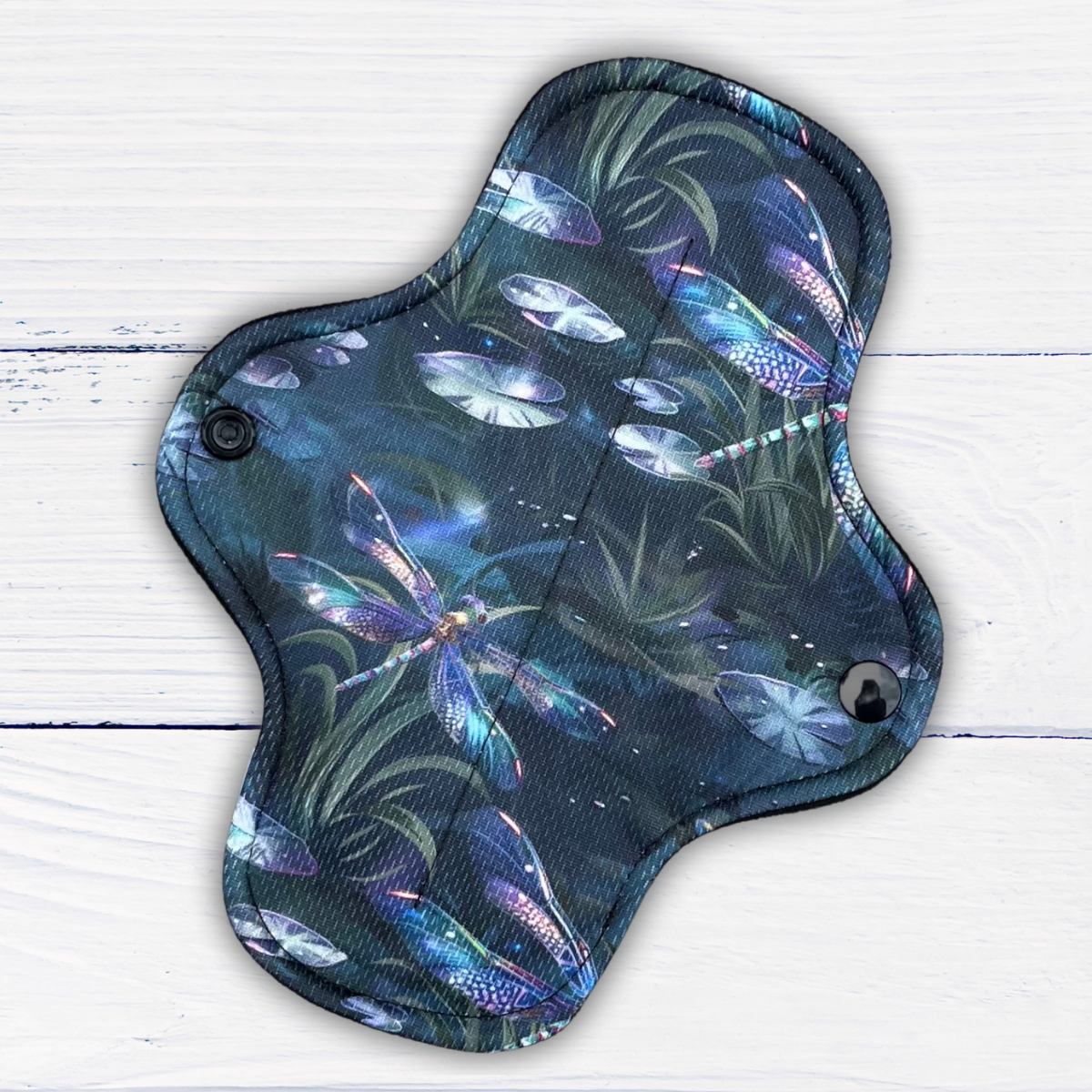 reusable pad in a dragonfly print athletic wicking jersey on a rustic white wood background
