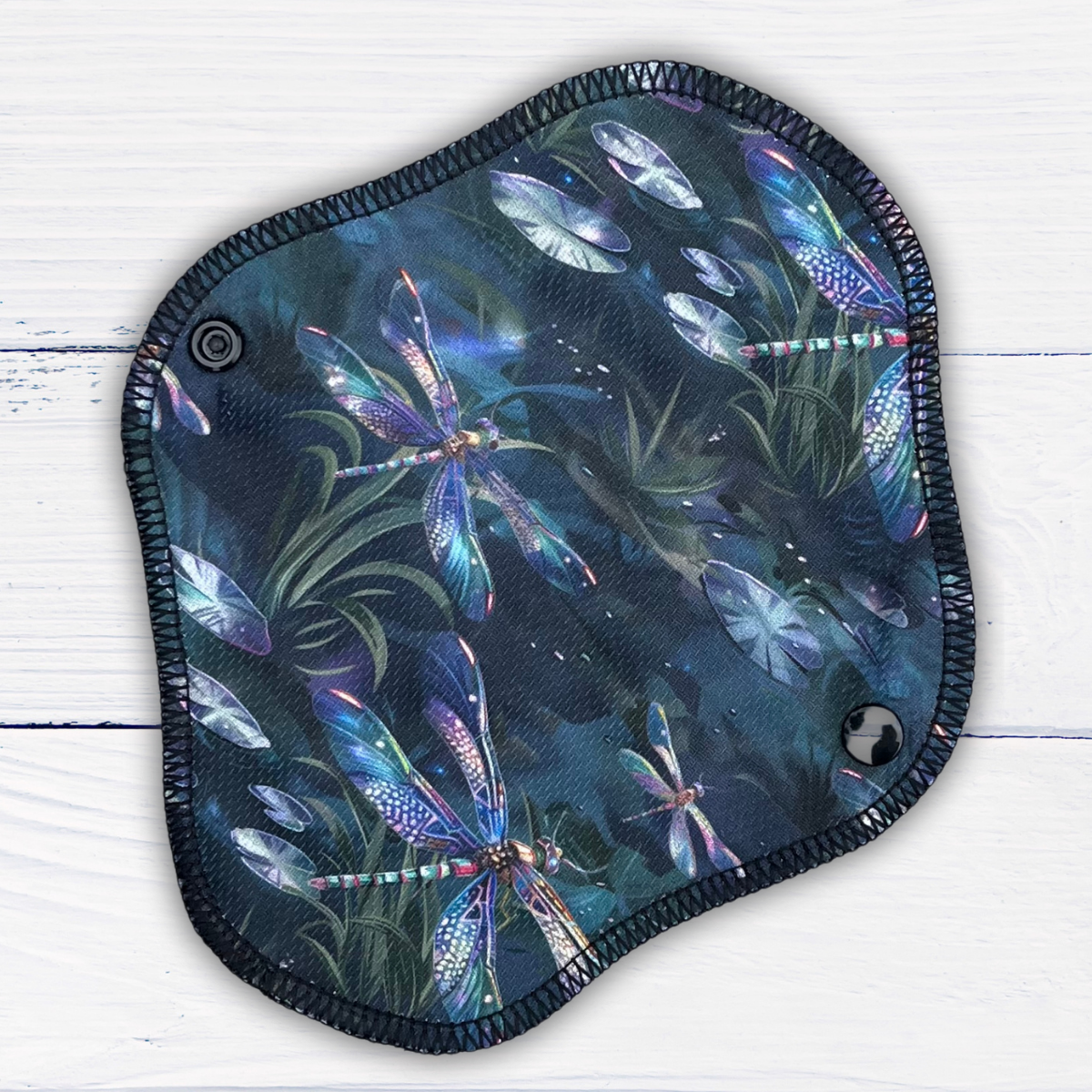 reusable pantyliner in a dragonfly print athletic wicking jersey on a rustic white wood background
