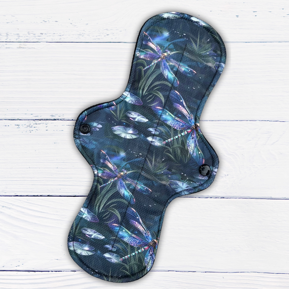 long heavy absorbency reusable pad in a dragonfly print athletic wicking jersey on a rustic white wood background