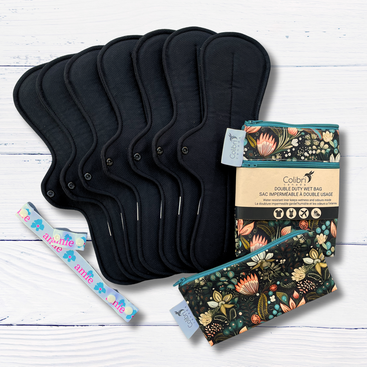 Set of black pads with floral-patterned bags on a white wooden surface
