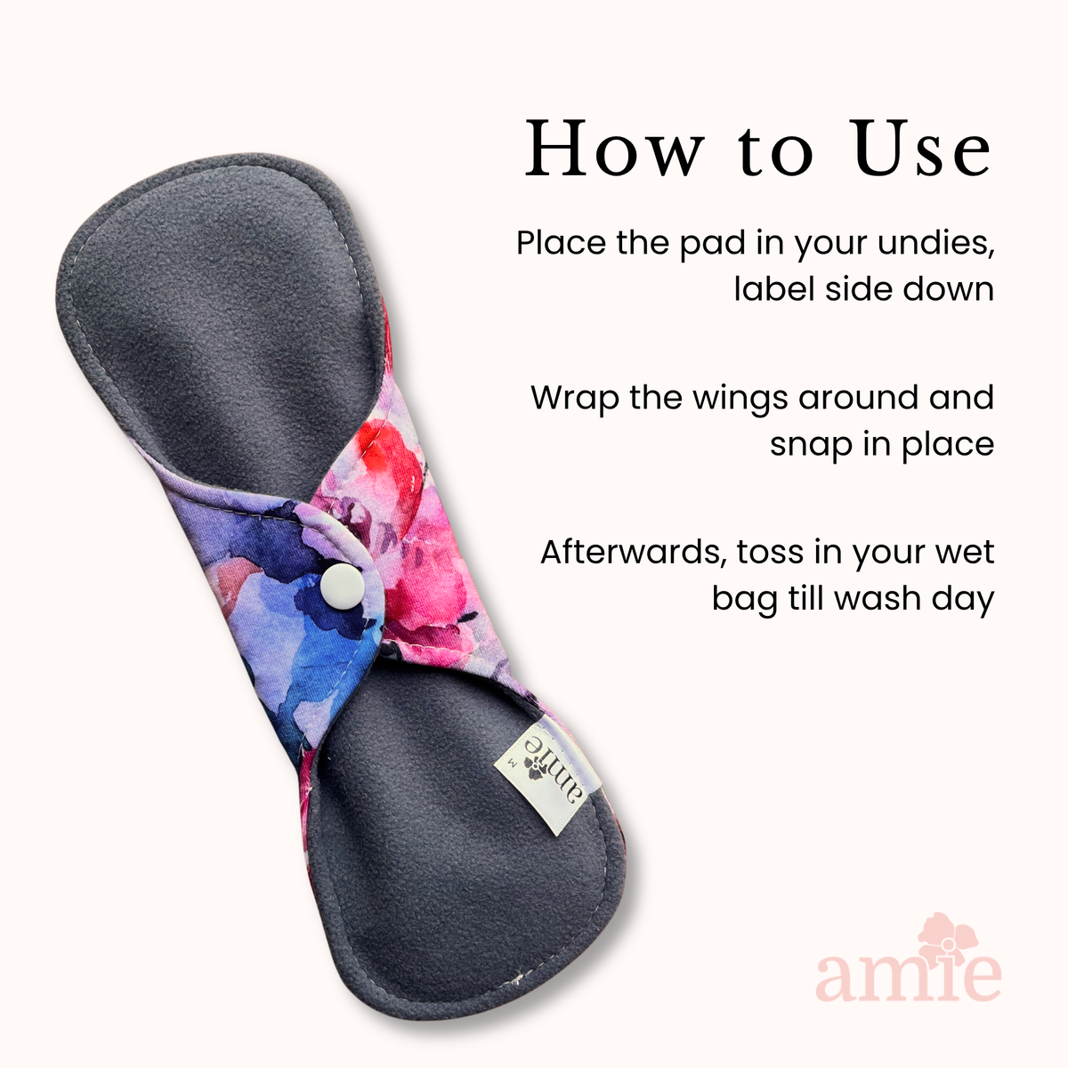 A reusable cloth sanitary pad with a dark gray backing and a colourful floral print in purple, pink, and blue, shown on a light peach background with 'How to Use' instructions and the Amie logo.