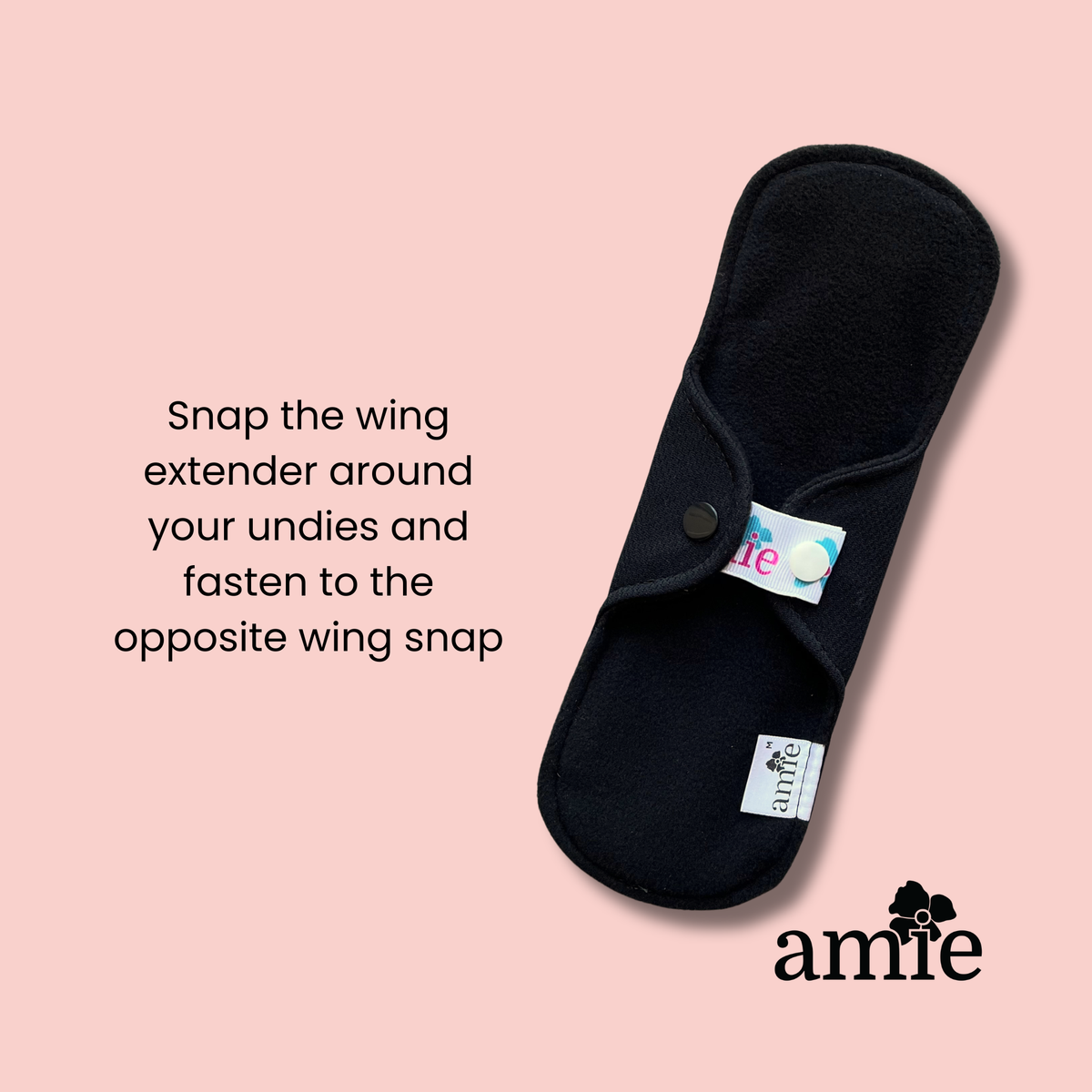 wing extender attached to a black reusable pad with 'amie' branding on a blush background with instructions on how to use it