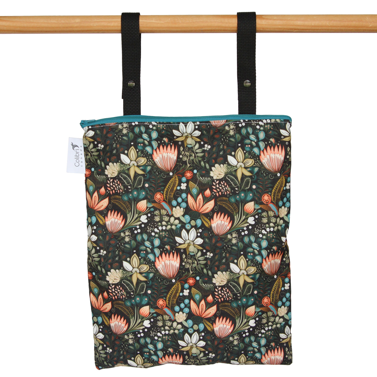 A reusable fabric tote bag with a dark floral print, hanging from black straps on a wooden rod against a white background.