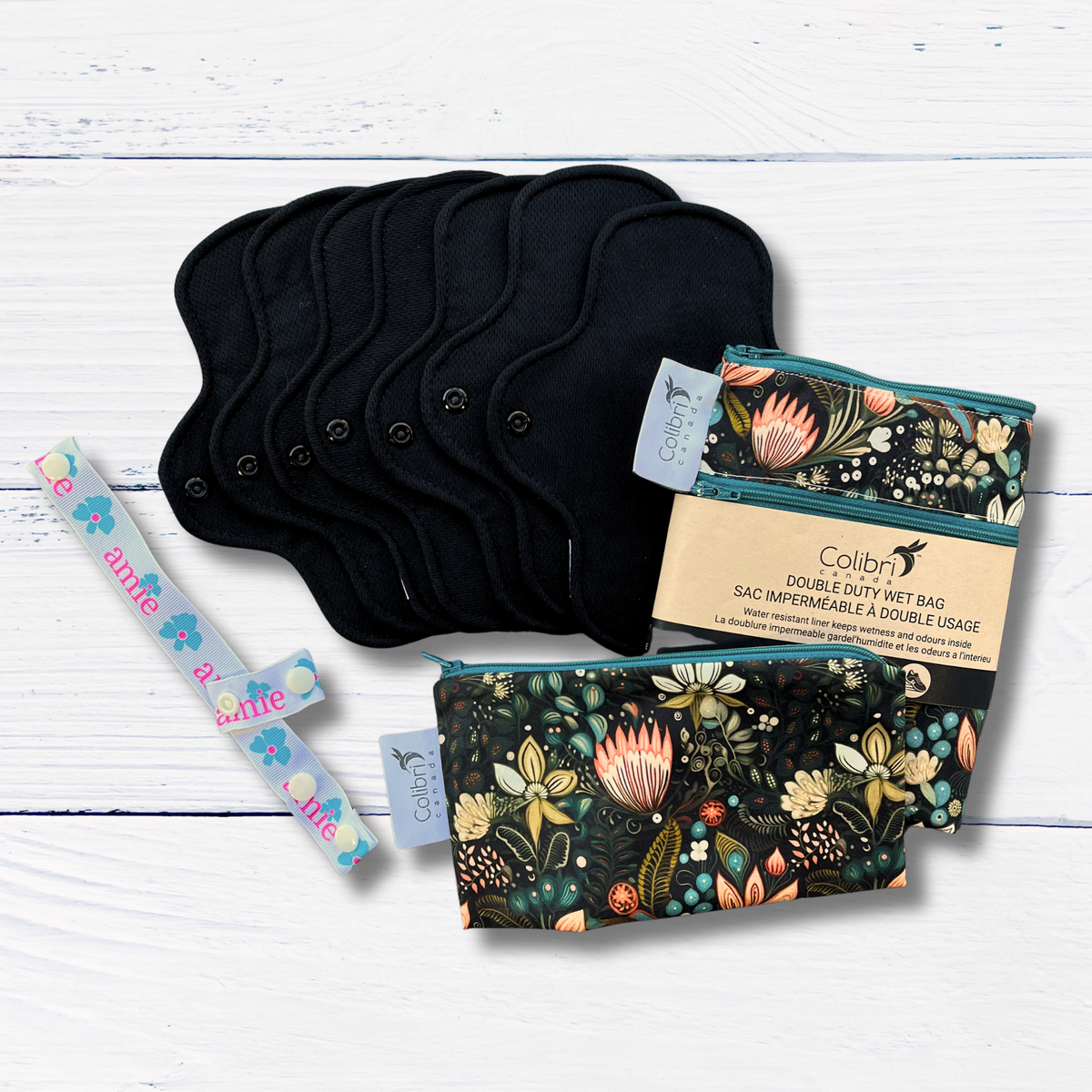 Black cloth pads, floral-patterned bags, and a drying strap on a white wooden surface