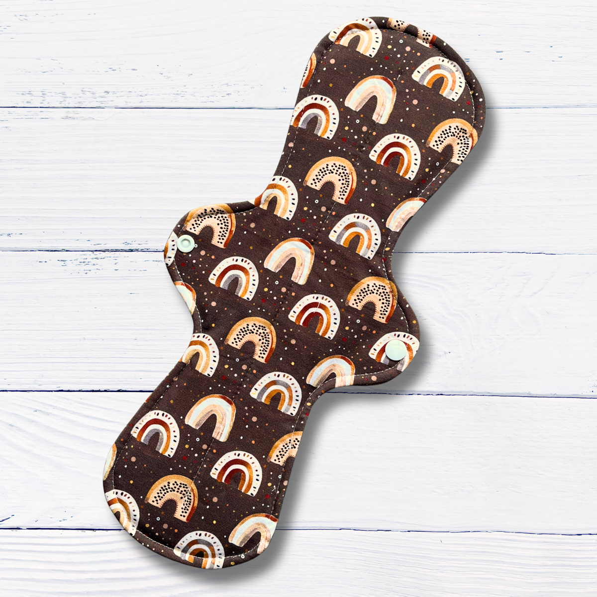 Brown cloth pad with rainbow pattern on a white wooden background