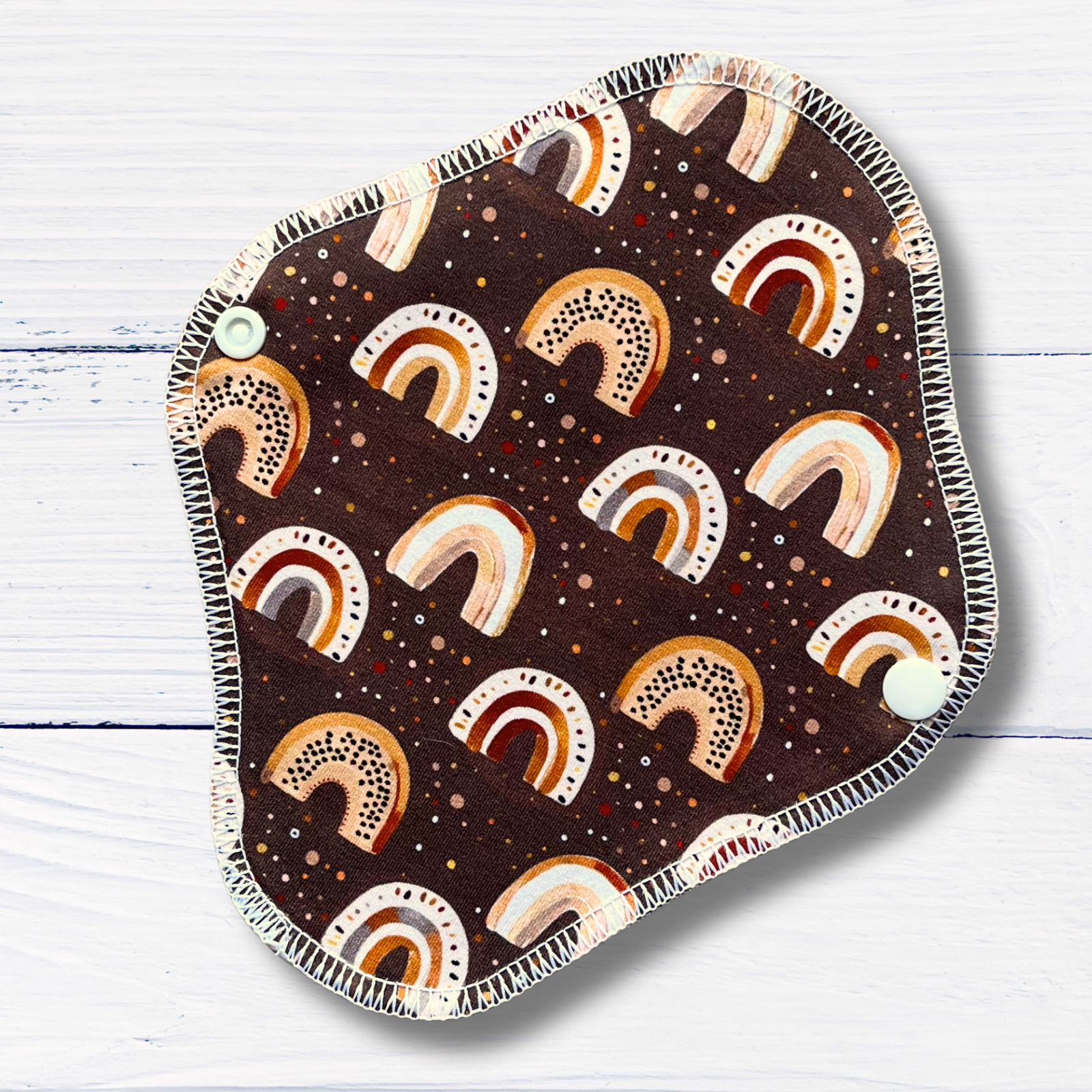 reusable liner with an earthy toned rainbow print on a white wooden surface