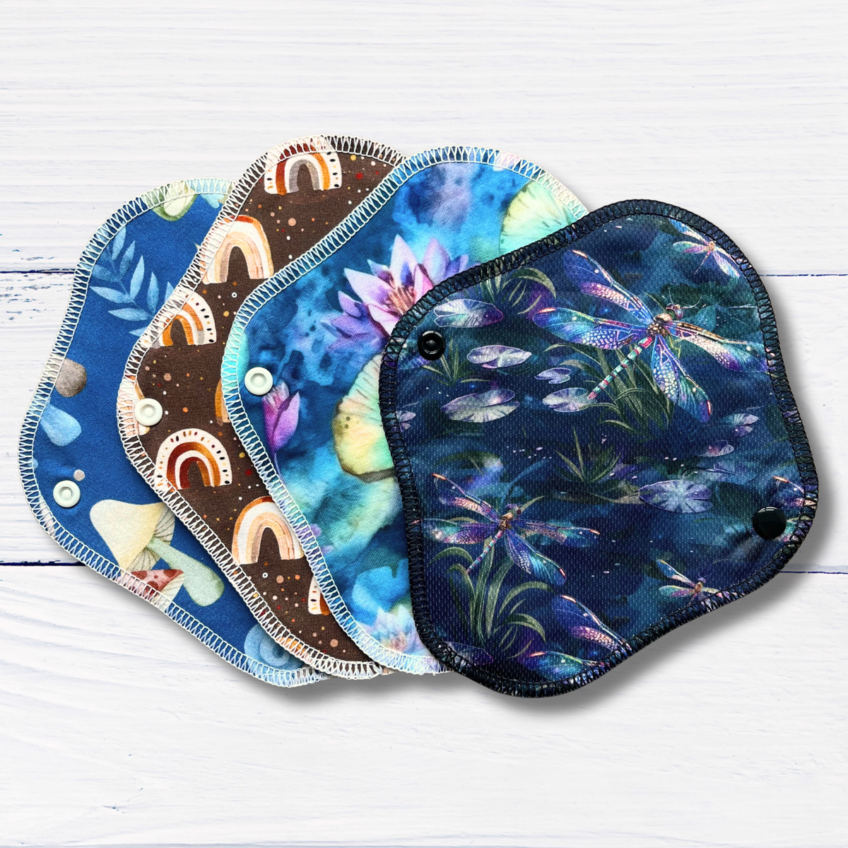 Set of colourful reusable liners with nature-themed designs on a white wooden surface