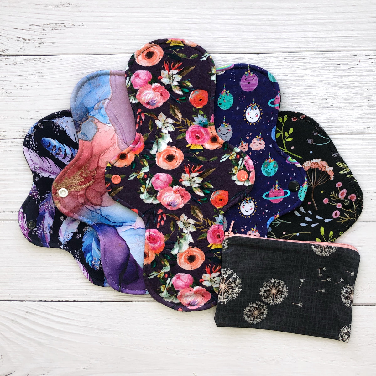basic reusable pad starter set with 5 colourful reusable pads in floral and other prints and a dandelion print small wetbag